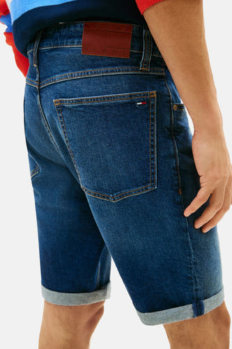 Short en jean denim bleu marine de TOMMY JEANS avec une étiquette en cuir marron sur la ceinture, un logo drapeau sur la poche et des ourlets retroussés.