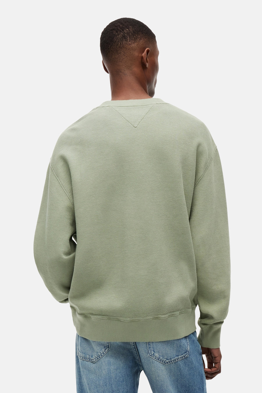 Pull vert à col rond de TOMMY JEANS, avec texture gaufrée et surpiqûre en V au niveau de la nuque, vu de dos sur un homme.