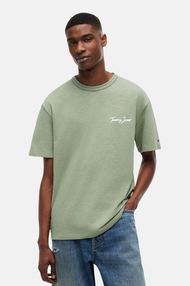 T-shirt vert à manches courtes TOMMY JEANS, avec tissu chiné, logo script blanc et logo drapeau, porté par un mannequin.