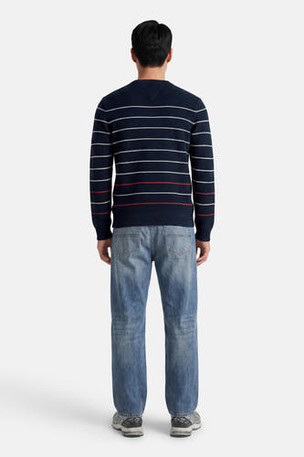Blauwe ronde hals trui met witte en rode strepen van TOMMY JEANS, achterzijde weergegeven op model in lichtblauwe jeans