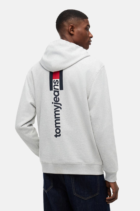 Sweatshirt à capuche gris de TOMMY JEANS, avec une rayure verticale rouge-marine et le logo 'tommyjeans' dans le dos.