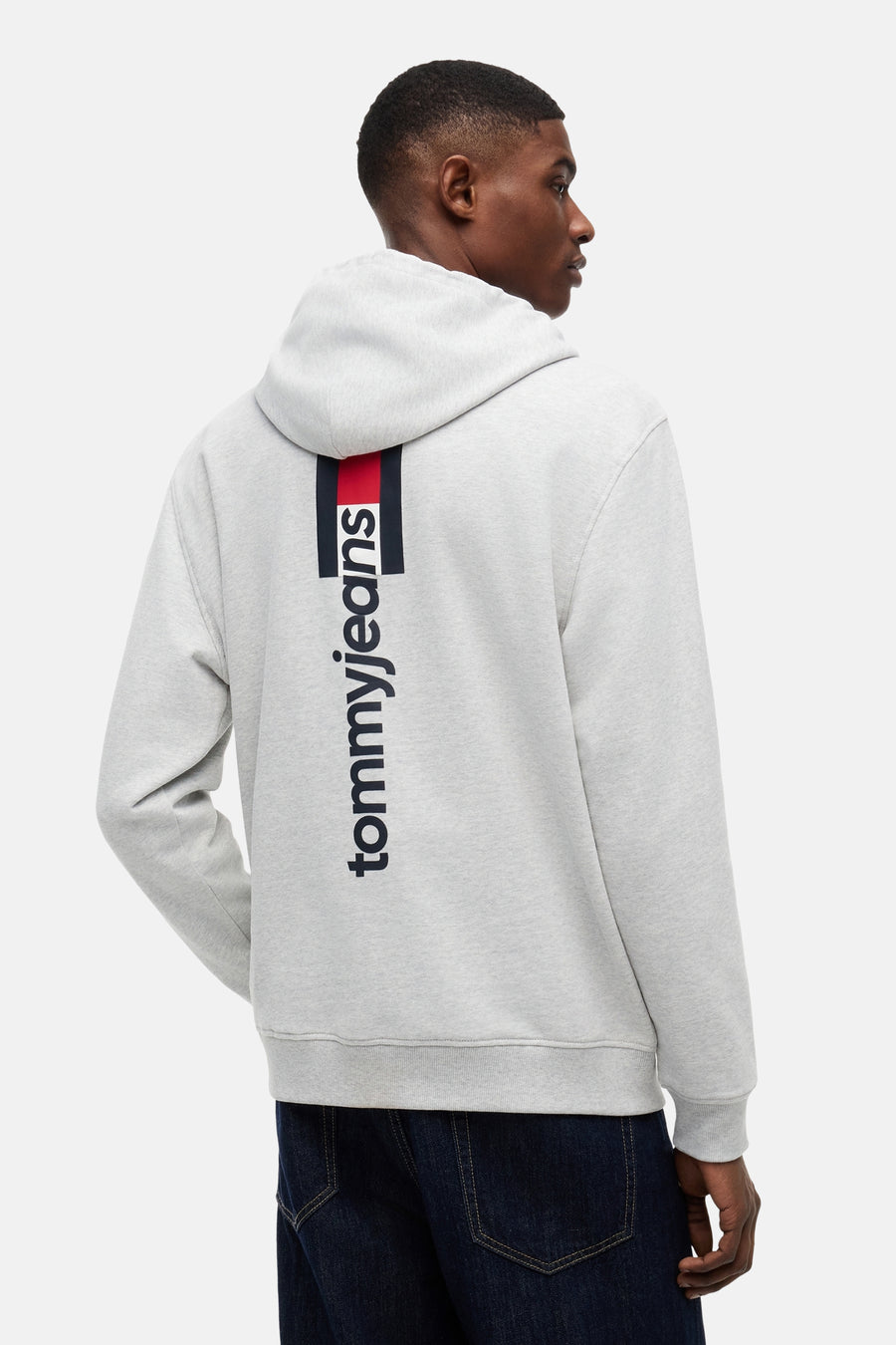 Sweatshirt à capuche gris de TOMMY JEANS, avec une rayure verticale rouge-marine et le logo 'tommyjeans' dans le dos.