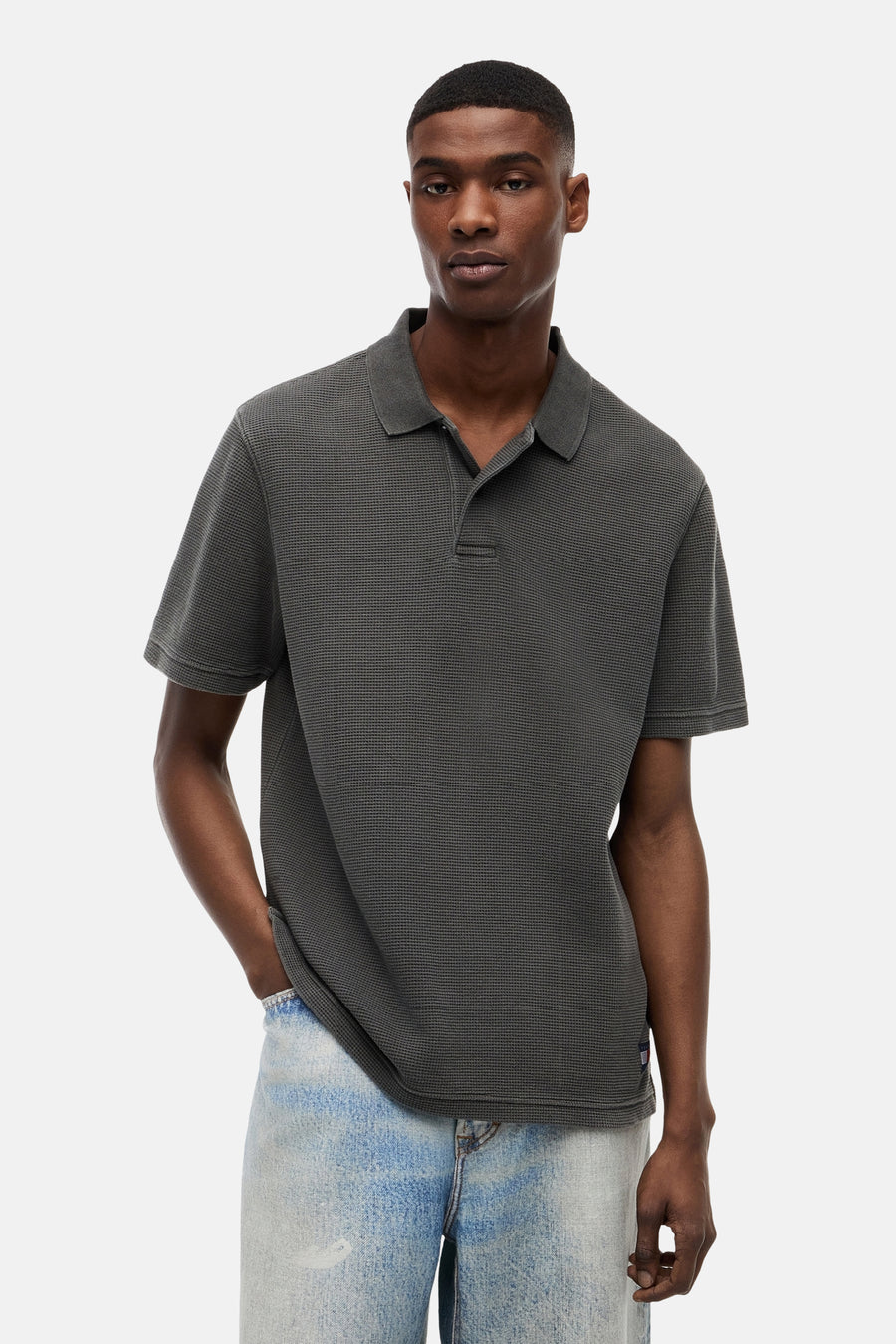 Zwart geruit polo van TOMMY JEANS, front view, met korte mouwen en ribbeltextuur, gedragen met lichtblauwe jeans