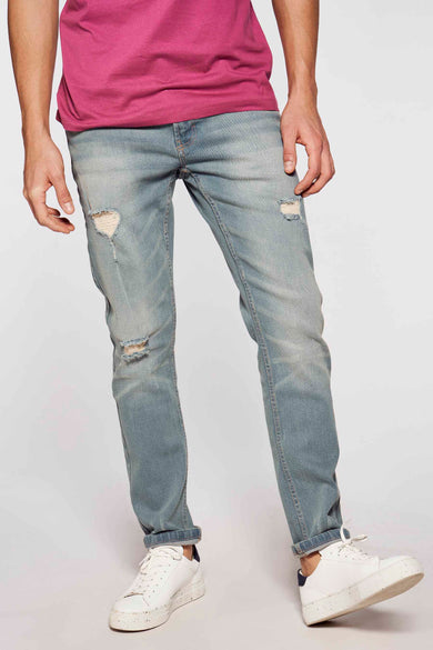 Jean slim en denim bleu clair de DENIM PROJECT, avec des déchirures et des jambes retroussées, associé à un T-shirt rose et des baskets blanches.