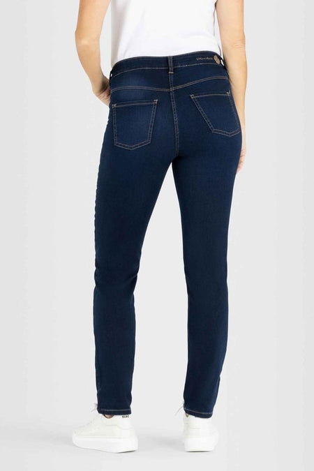 Donkerblauwe straight jeans van MAC, met stiksels op de achterzakken, gedragen met een wit T-shirt en sneakers.
