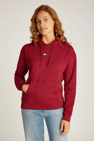 Pull-over rouge avec capuche de TOMMY JEANS, avec poche et jeans bleu clair.