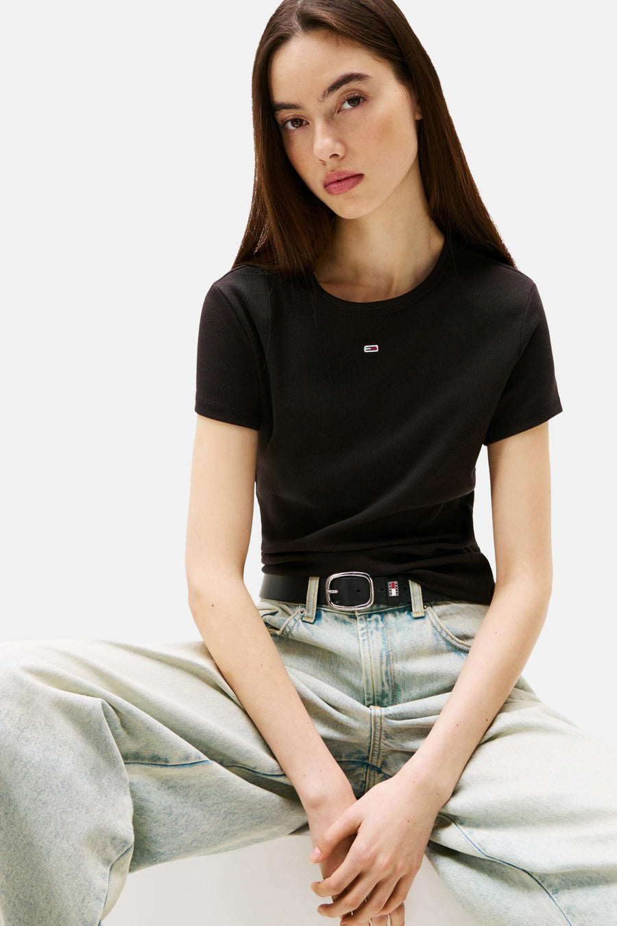 Zwart korte mouwen T-shirt van TOMMY JEANS met ribstructuur en klein logo, gedragen met lichte jeans en zwarte riem, front view.