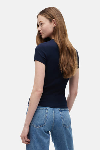 T-shirt côtelé bleu foncé de TOMMY JEANS, à manches courtes et coupe ajustée, porté de dos avec un jean bleu.