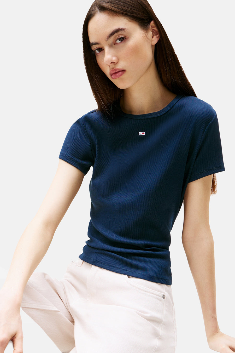 T-shirt bleu côtelé à manches courtes TOMMY JEANS avec petit logo, porté par un mannequin avec un pantalon clair.