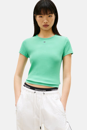 T-shirt vert à manches courtes TOMMY JEANS, coupe courte et porté avec un jogging blanc.