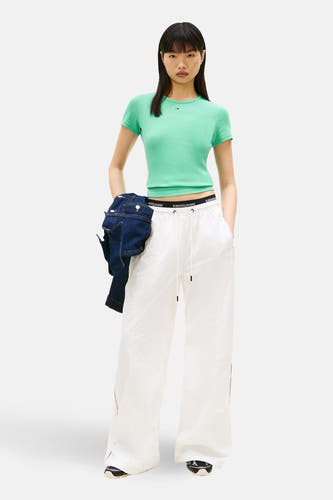 Groen T-shirt met korte mouwen van TOMMY JEANS, met een korte pasvorm en gedragen met witte joggingbroek.
