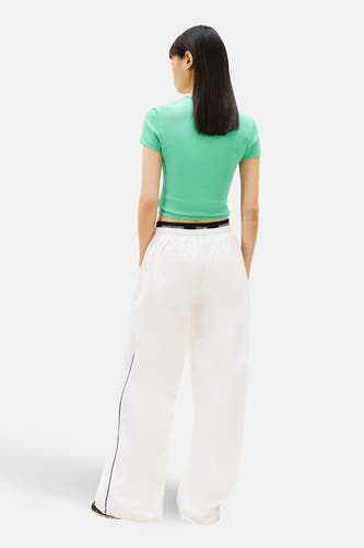 T-shirt vert à manches courtes Tommy Jeans, vu de dos avec une ceinture visible et un pantalon blanc.