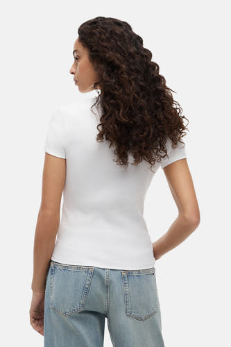 T-shirt blanc côtelé à manches courtes de TOMMY JEANS, vu de dos sur une femme portant un jean bleu clair.