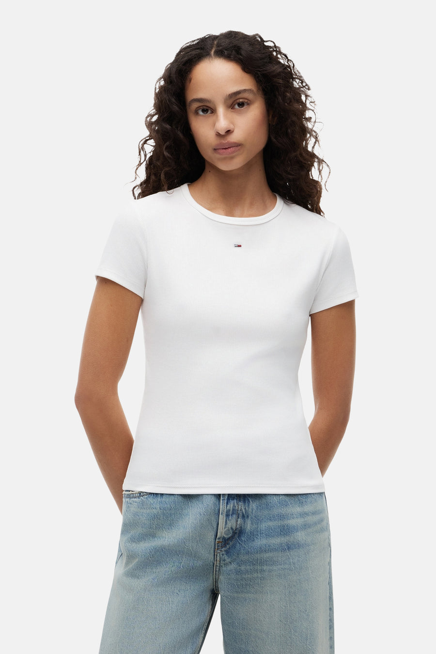 T-shirt blanc côtelé de TOMMY JEANS avec petit logo sur la poitrine, porté par un mannequin avec un jean clair.