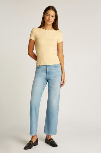 T-shirt jaune à manches courtes de TOMMY JEANS, associé à des jeans larges et des loafers noirs.
