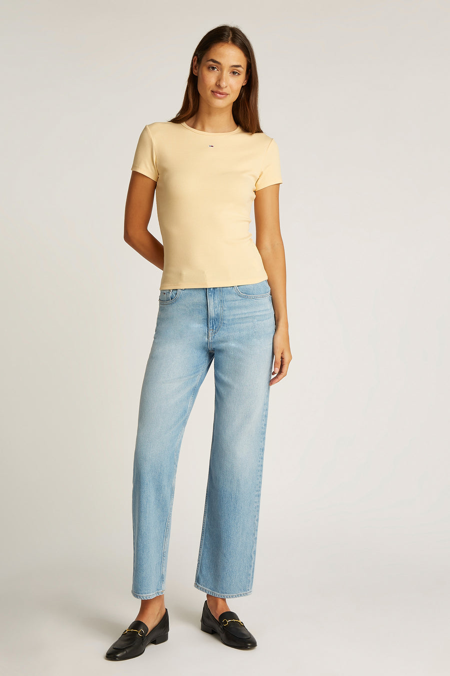 T-shirt jaune à manches courtes de TOMMY JEANS, associé à des jeans larges et des loafers noirs.