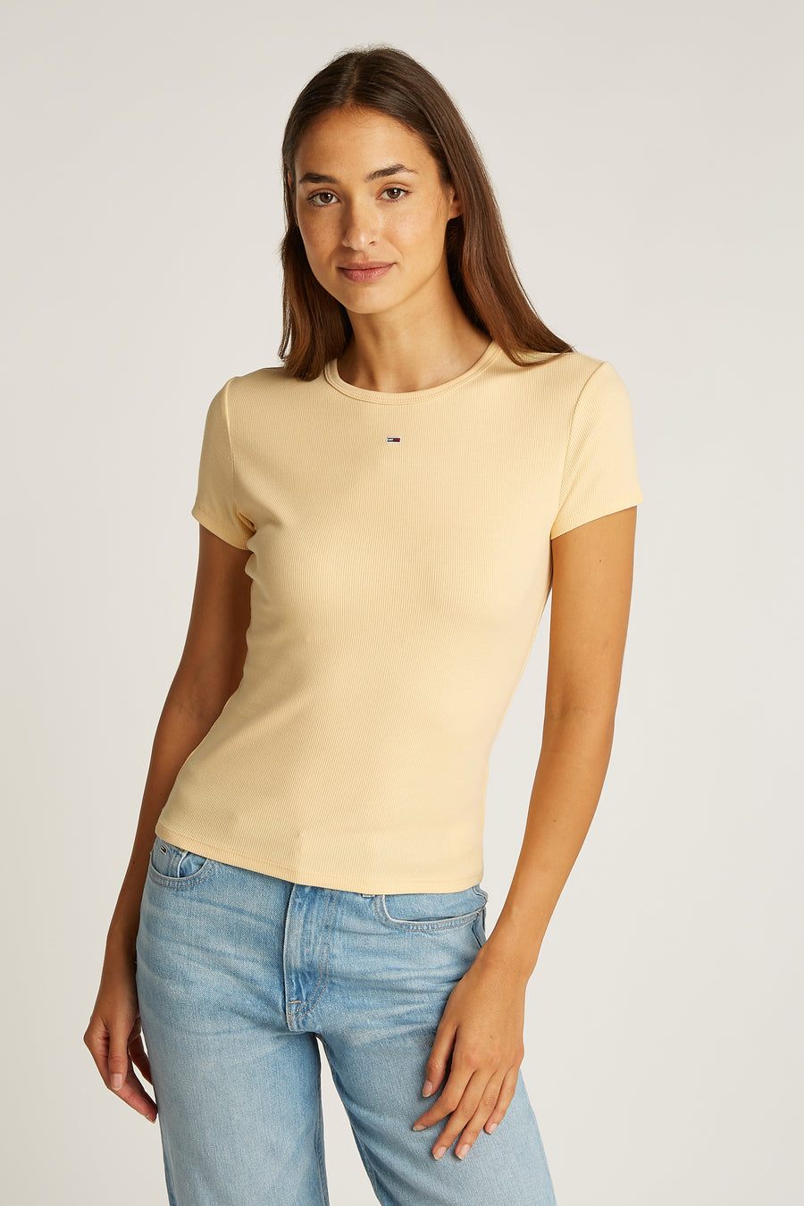 T-shirt jaune à manches courtes de TOMMY JEANS, avec une texture côtelée, porté avec un jean bleu.