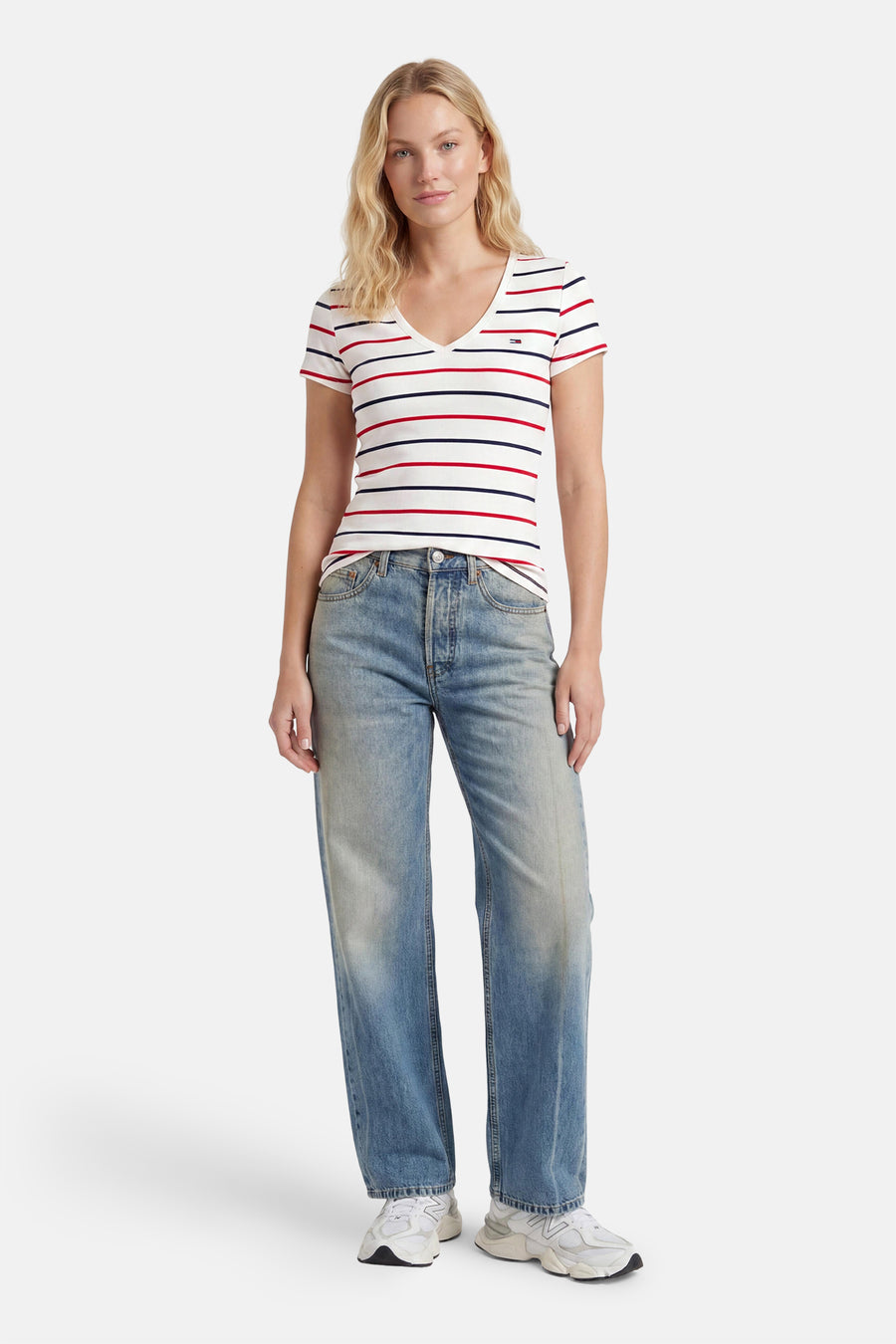 Multicolor gestreepte korte mouwen T-shirt van TOMMY JEANS, met V-hals en klein logo, gedragen met lichtblauwe jeans en witte sneakers, front view.