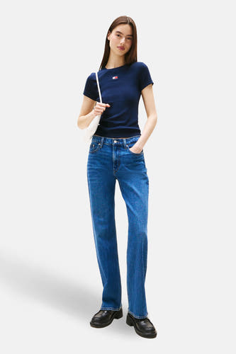 T-shirt bleu à manches courtes de TOMMY JEANS, avec un petit logo et associé à un jean et des chaussures noires.