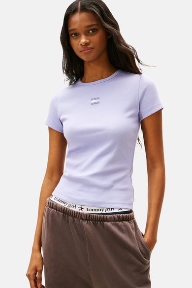 T-shirt bleu marine à manches courtes de TOMMY JEANS, avec un pantalon de jogging marron et des chaussures sur l'arrière.