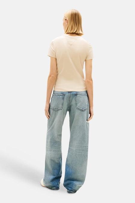 T-shirt beige de TOMMY JEANS, vue de dos, avec jean bleu ample et chaussures blanches.