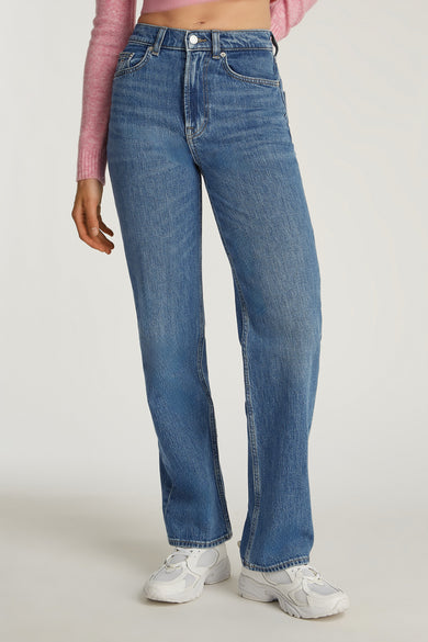 Jean slim de denim bleu de TOMMY JEANS, avec des surpiqures sur les poches arrière et une étiquette en cuir.