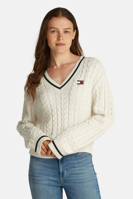 T-shirt blanc à col V de TOMMY JEANS, avec un motif côtelé et des détails rayés, associé à un jean.