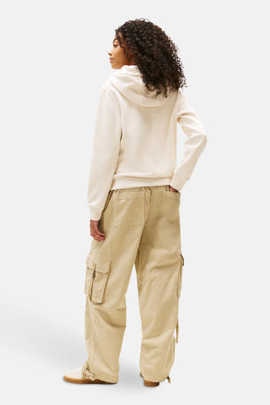 Pull beige de TOMMY JEANS, associé à un pantalon cargo kaki, vu de derrière.