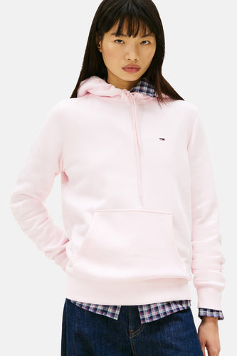 Roze hoodie met Tommy Hilfiger logo, gedragen over een geruit overhemd.