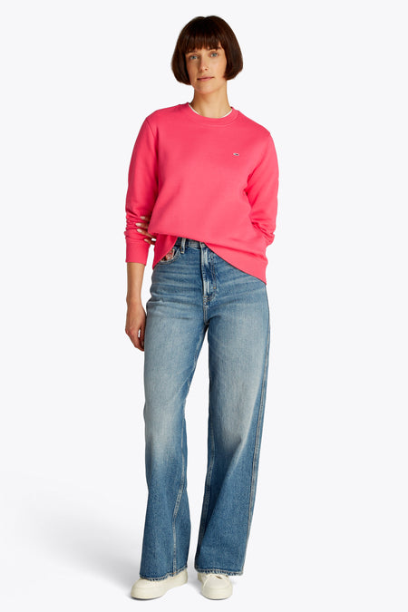 Pull-over rose de TOMMY JEANS, associé à un jean et des chaussures crème.
