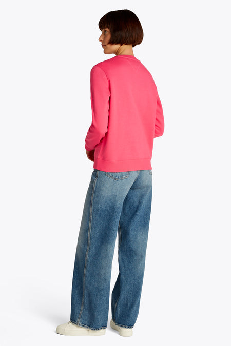 Sweater rose de TOMMY JEANS, porté avec des jeans bleus à larges jambes et des chaussures crème, vue arrière.