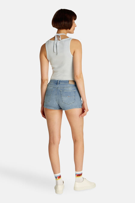 Short de denim bleu clair de TOMMY JEANS, avec des poches courtes et porté avec des chaussettes blanches et des baskets.