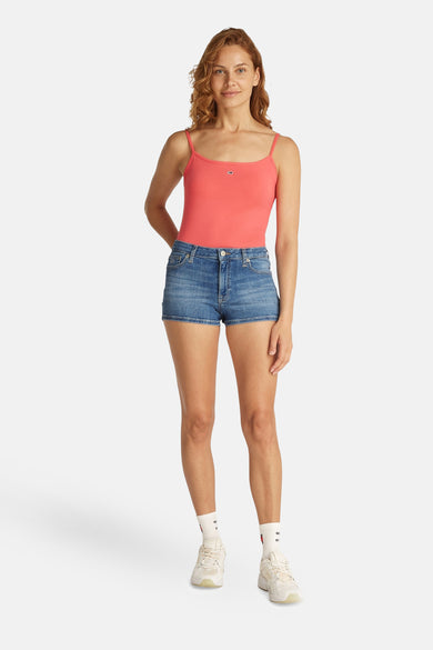 Denim short van TOMMY JEANS, gedragen met een roze top en witte sportsokken met logo en witte sneakers.
