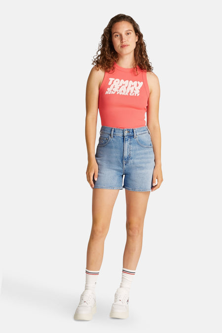 Short de denim bleu clair court de TOMMY JEANS, associé à un haut rose et des baskets blanches avec des chaussettes.