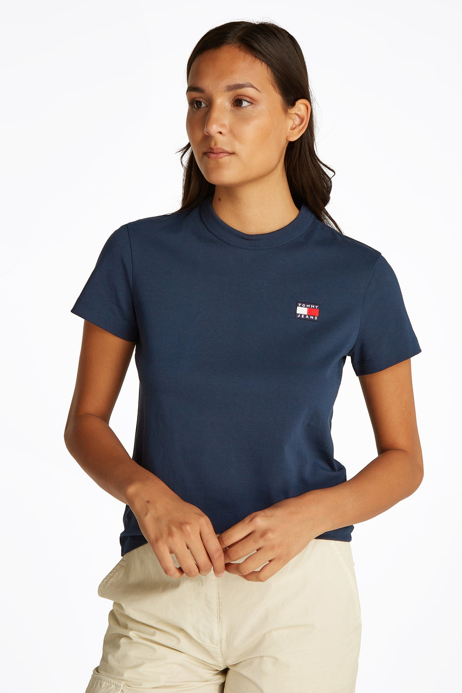 T-shirt bleu à manches courtes de TOMMY JEANS, vue arrière avec un pantalon cargo beige et des chaussures blanches.