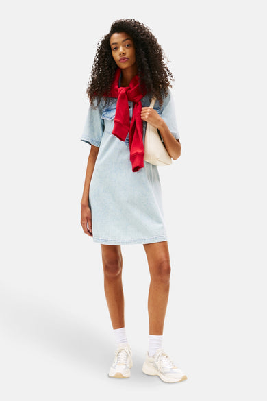 Jupe en denim bleu clair à manches courtes de TOMMY JEANS, avec un pull rouge et un sac blanc.