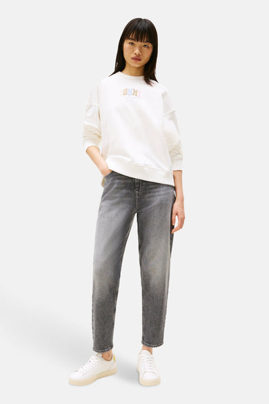 Jean mom en denim gris moyen de TOMMY JEANS, porté avec un t-shirt blanc et des baskets blanches.