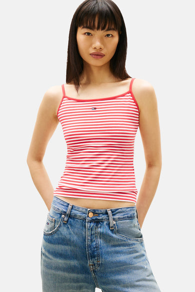 Haut multicolore de TOMMY JEANS avec des rayures rouges et blanches, porté avec un jean ample et des baskets.