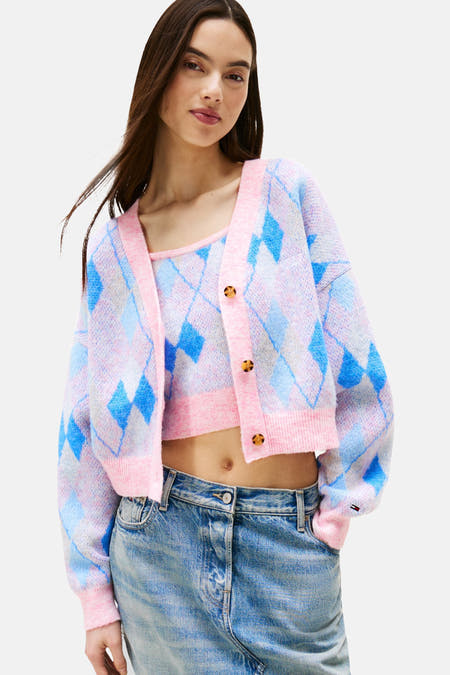 Cardigan rose de TOMMY JEANS avec imprimé à carreaux bleus, porté avec un top coordonné et des jeans.