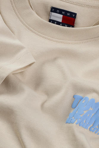 T-shirt écru à manches courtes de Tommy Jeans, avec une impression bleue claire sur l'avant.