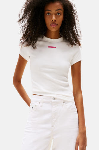 T-shirt écru à manches courtes de TOMMY JEANS, porté avec un jean blanc et des baskets.