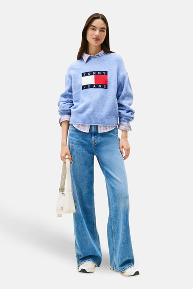 T-shirt bleu avec col rond de Tommy Jeans, porté sur un chemisier à carreaux avec des jeans larges et une veste de éau.