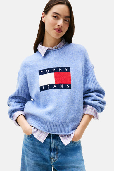 T-shirt bleu avec col rond de TOMMY JEANS, porté sur un chemisier à carreaux, avec des jeans en denim.