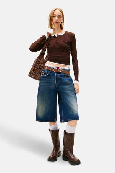 Short de denim bleu marine TOMMY JEANS, avec une ceinture marron, associé à un haut marron et des bottes.