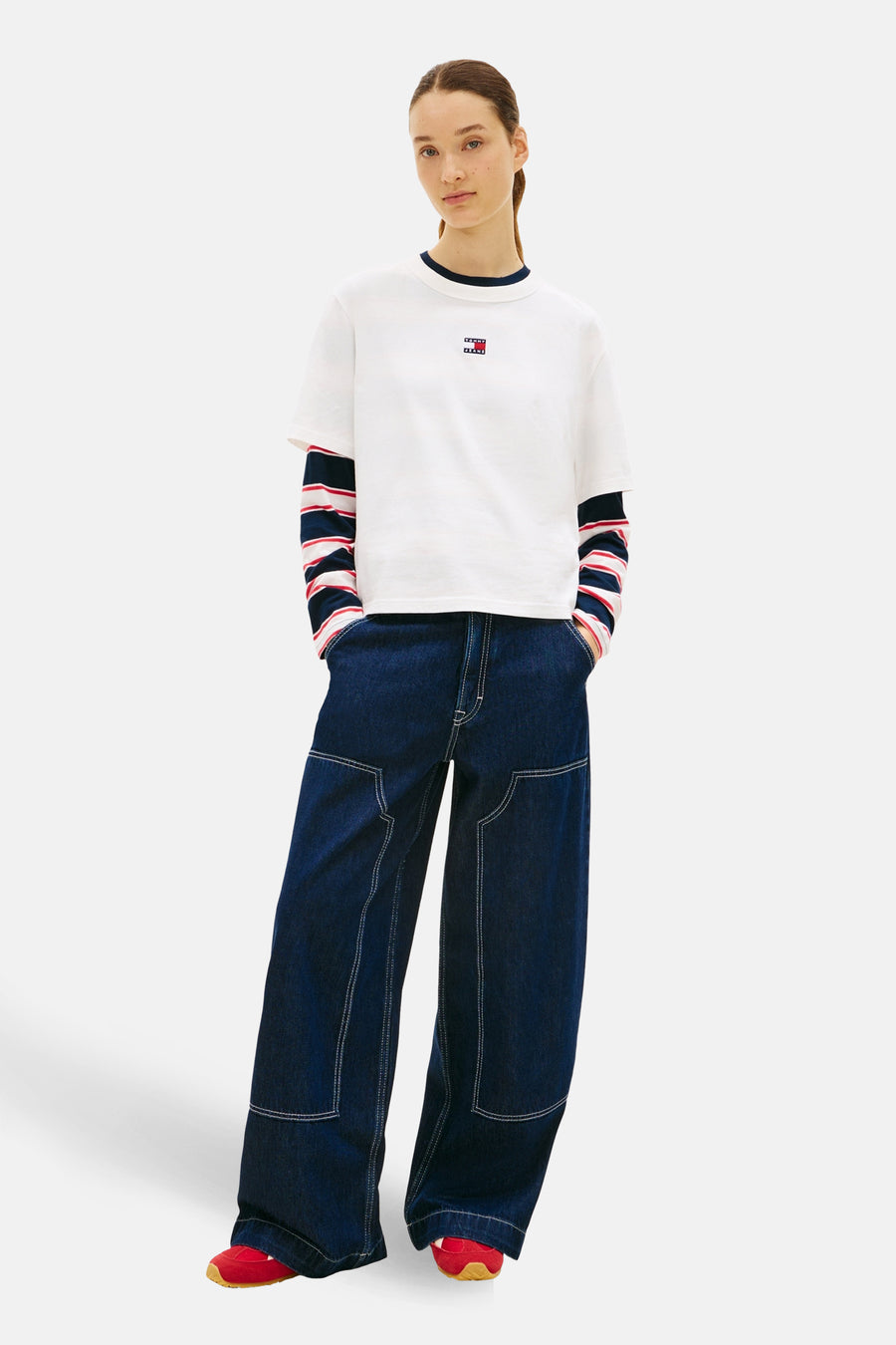 T-shirt blanc à manches courtes de TOMMY JEANS, modèle décontracté vu de l'arrière, associé à des jeans larges.