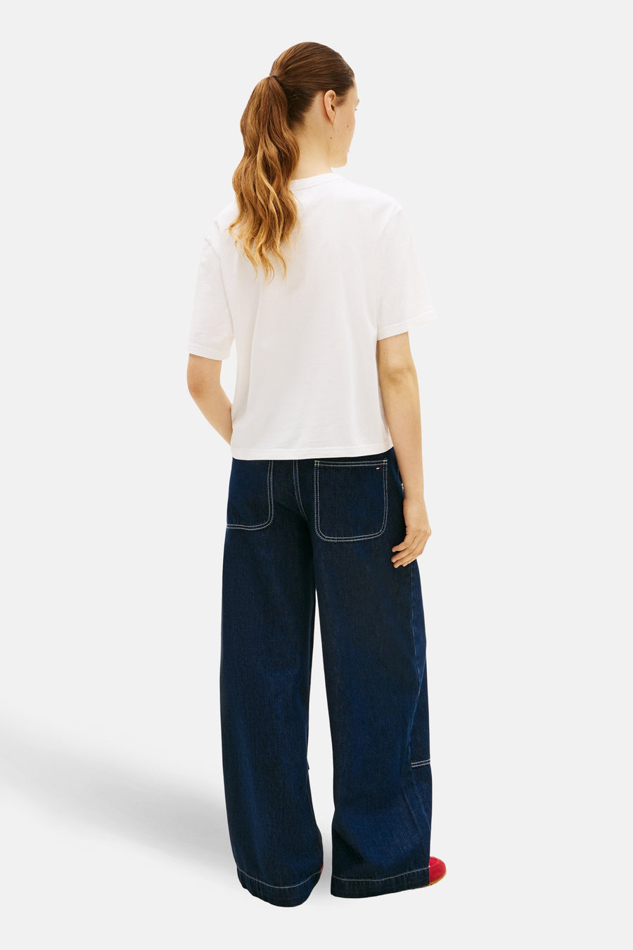 Wit T-shirt met korte mouwen van TOMMY JEANS, losvallend model achterkant gezien, gecombineerd met wijde jeans.
