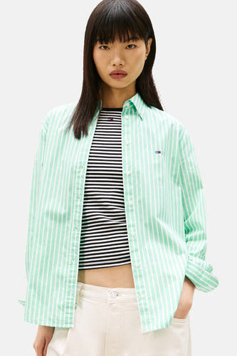 Chemise verte à rayures à manches longues de TOMMY JEANS, portée sur un haut rayé et associée à une casquette en jean.