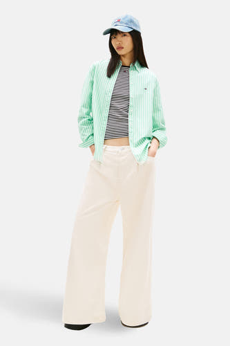 Groen gestreept overhemd met lange mouwen van TOMMY JEANS, gedragen over een gestreepte top en gecombineerd met een jeans pet.
