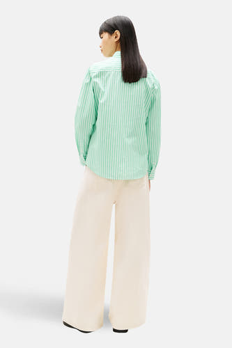 Chemise verte rayée à manches longues de TOMMY JEANS, avec manches longues et pantalon large de couleur crème.