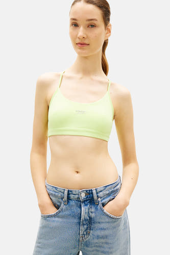 Haut court vert TOMMY JEANS avec logo, porté avec un sweat à capuche gris ouvert et un jean déchiré.